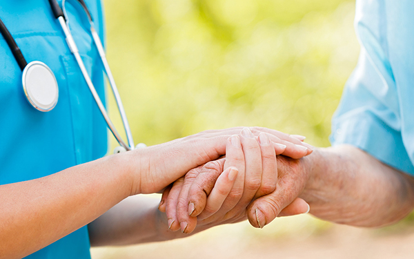 Doctor or nurse holding elderly lady's hands.